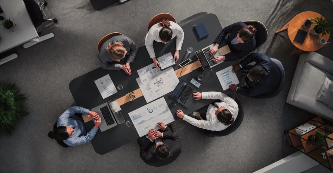 Equipe reunida em volta de uma mesa de trabalho, vista de cima